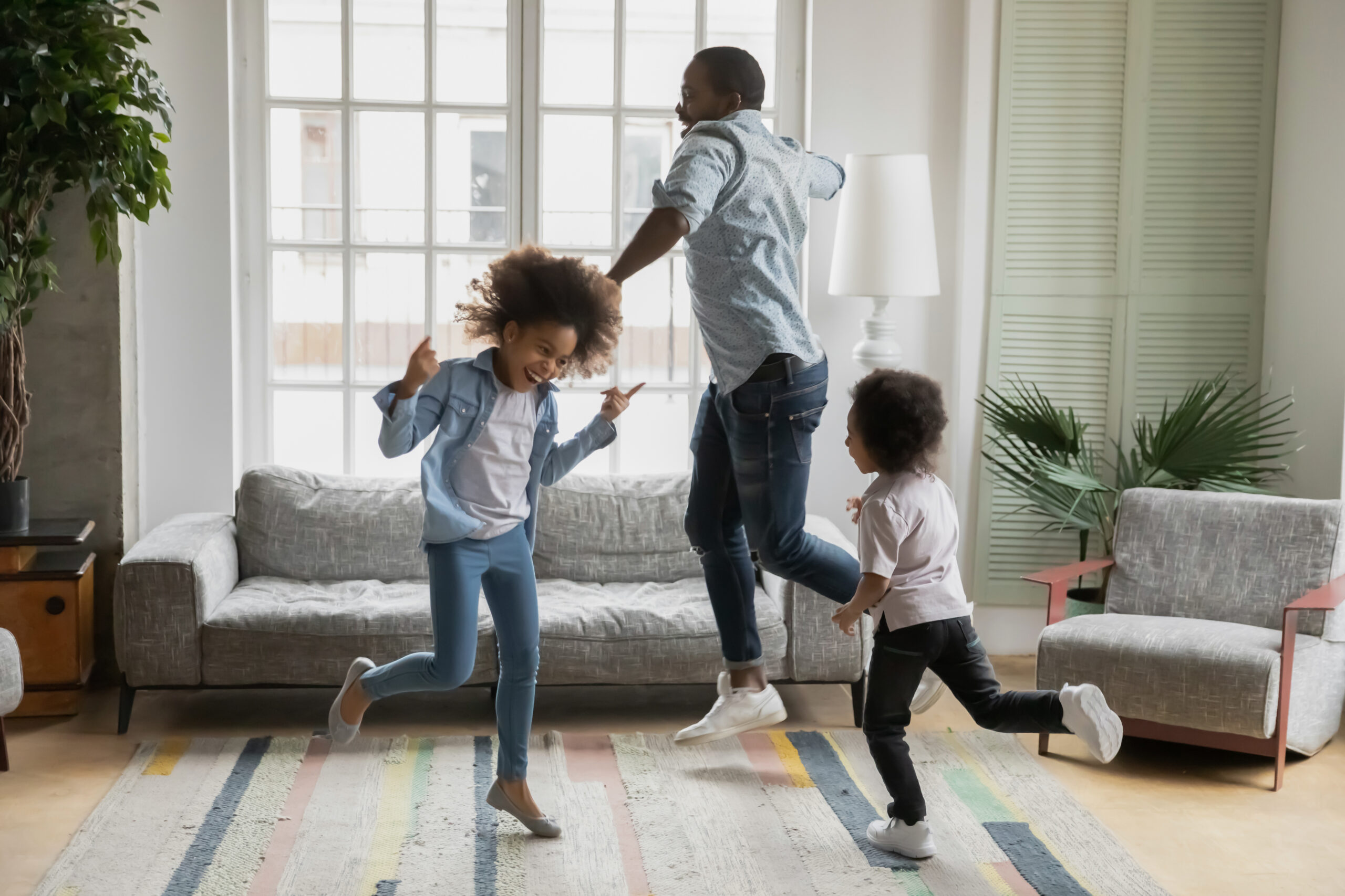African father son and daughter listening music dancing at home Active african funny dad little son and crazy daughter heavy metal or rock and roll lovers dancing in cozy living room relish life fooling around listening cool music scream with joy enjoy party hard